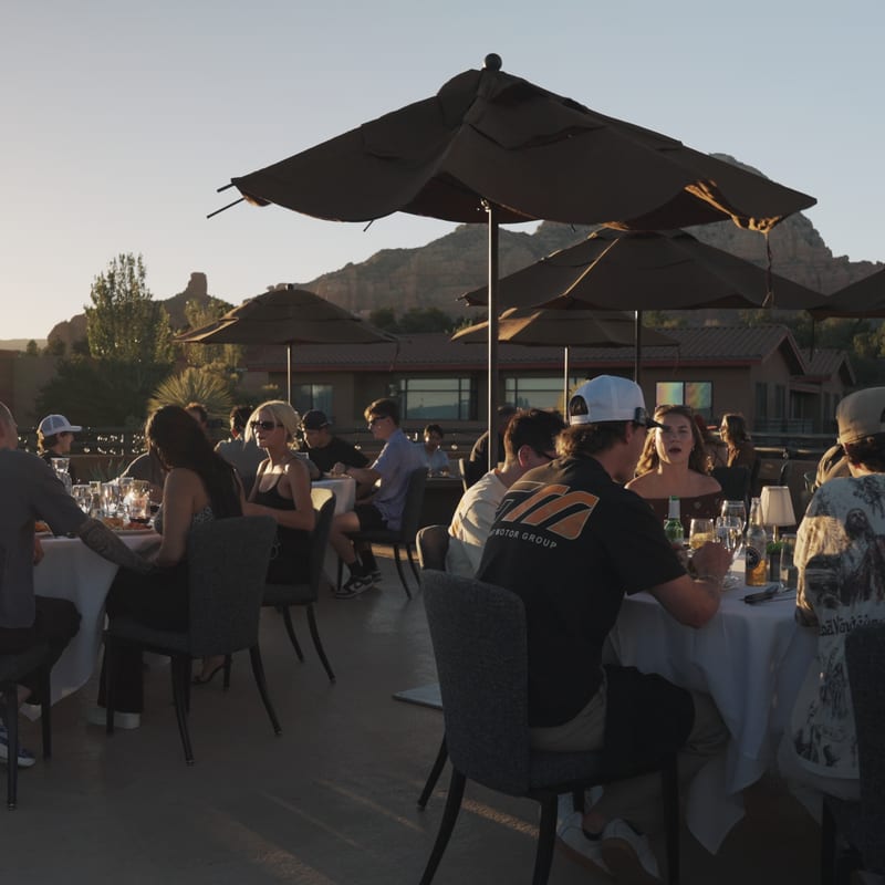 Rally guests seated at white-linen tables under umbrellas at a rooftop dinner in Sedona.