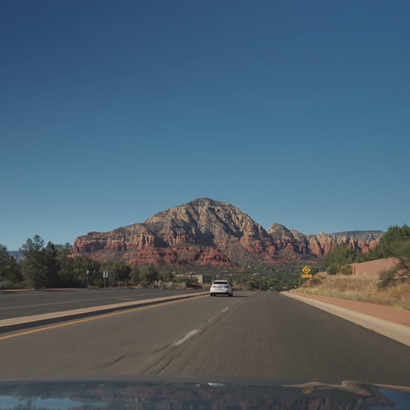 Sedona's red rock buttes ahead through the windshield as the rally rolls into town.